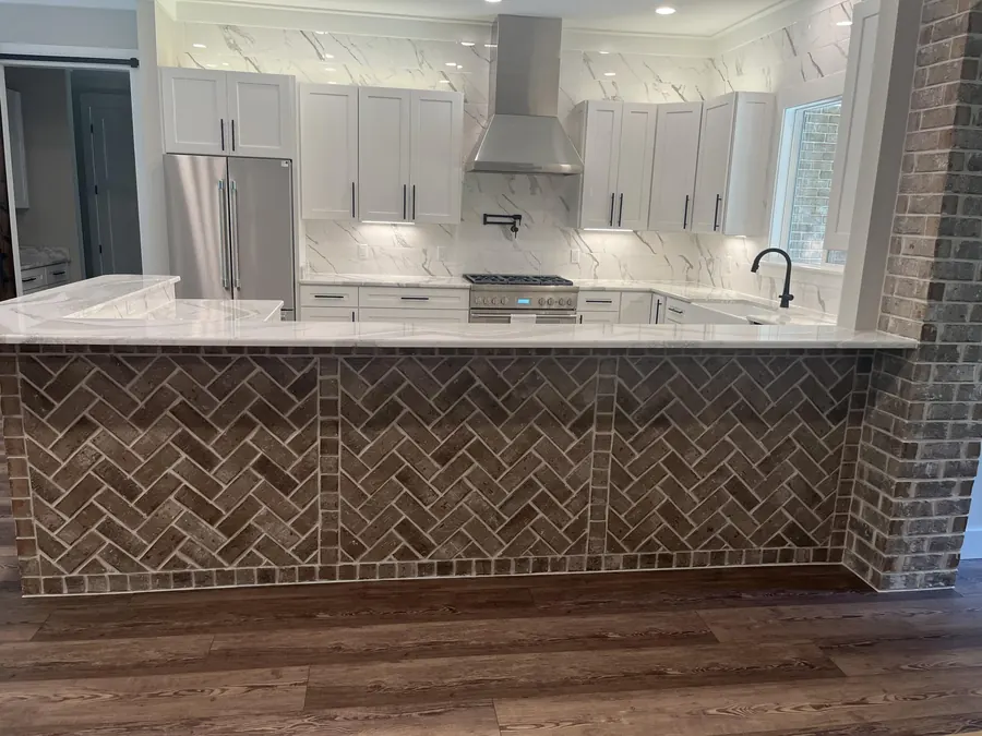 Kitchen island faced in herringbone brick with a white quartz top