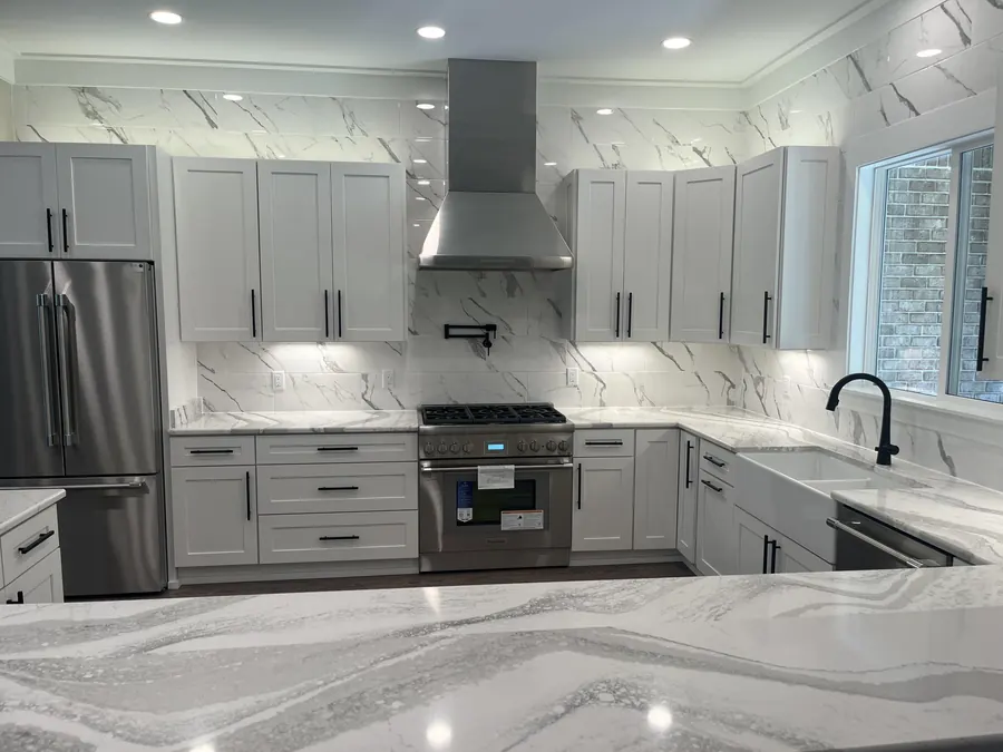 White shaker kitchen with a marble-look backsplash, stainless range hood and a 36-inch gas range