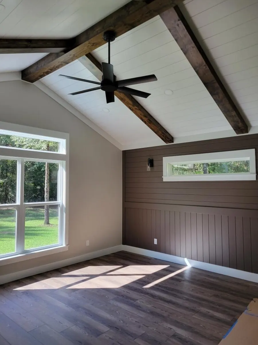 Primary bedroom with a vaulted ceiling, exposed stained beams and a ceiling fan