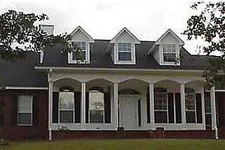 Brick home with three dormers and a deep arched front porch